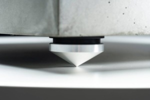 Detail hrotové nožky gramofonu EAT C-Dur Concrete z leštěného kovu na betonovém šasi.