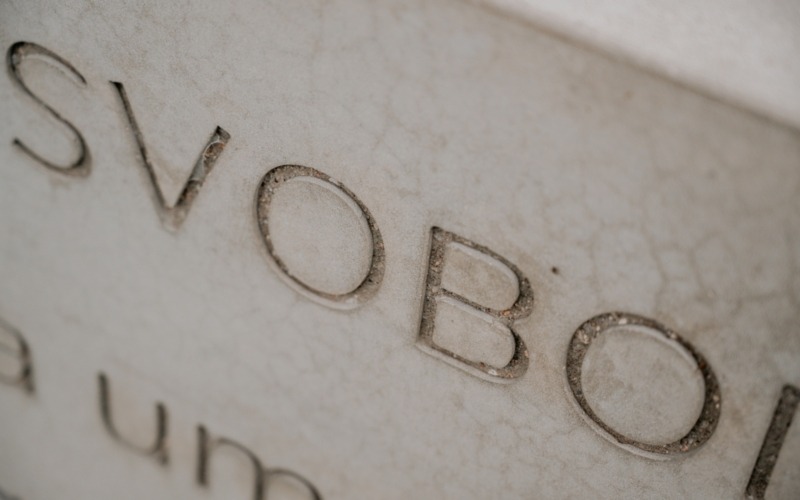 Detail prohloubeného slova Svobodu na betonové pamětní desce.