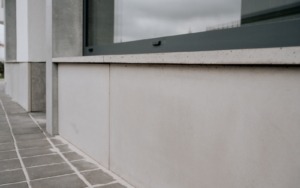 Detail parapetu s hladkým pohledovým betonem v exteriéru polyfunkčního domu.