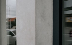 Betonový sloup a vstupní portál polyfunkčního domu se systémovými dveřmi.