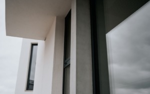 Detail rozhraní dvou odstínů pohledového betonu na fasádním prvku budovy.