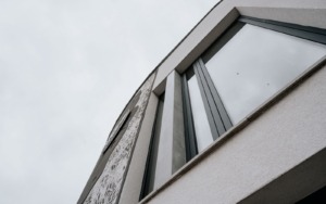 Detail šedobílé struktury a reliéfních motivů na betonové fasádě domu.