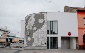 Fasáda polyfunkčního domu ve Šlapanicích s velkoformátovou uměleckou reliéfní betonovou stěnou.