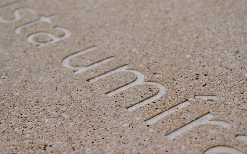 Detail grafického betonu s prohloubeným textem na prefabrikátu v parku Marie Restituty v Brně.