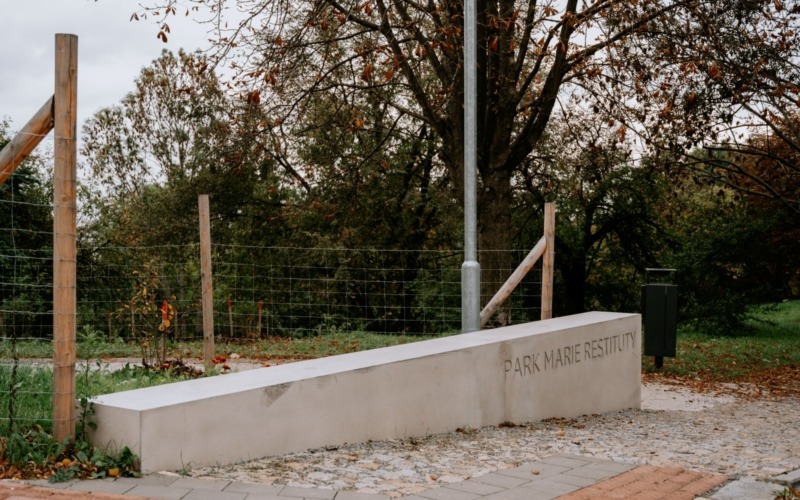 Boční pohled na dlouhou betonovou stěnu s názvem Park Marie Restituty.