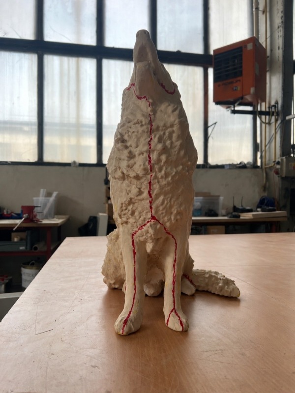 Čelní pohled na model sedícího psa s červenými liniemi na těle a předních tlapách.